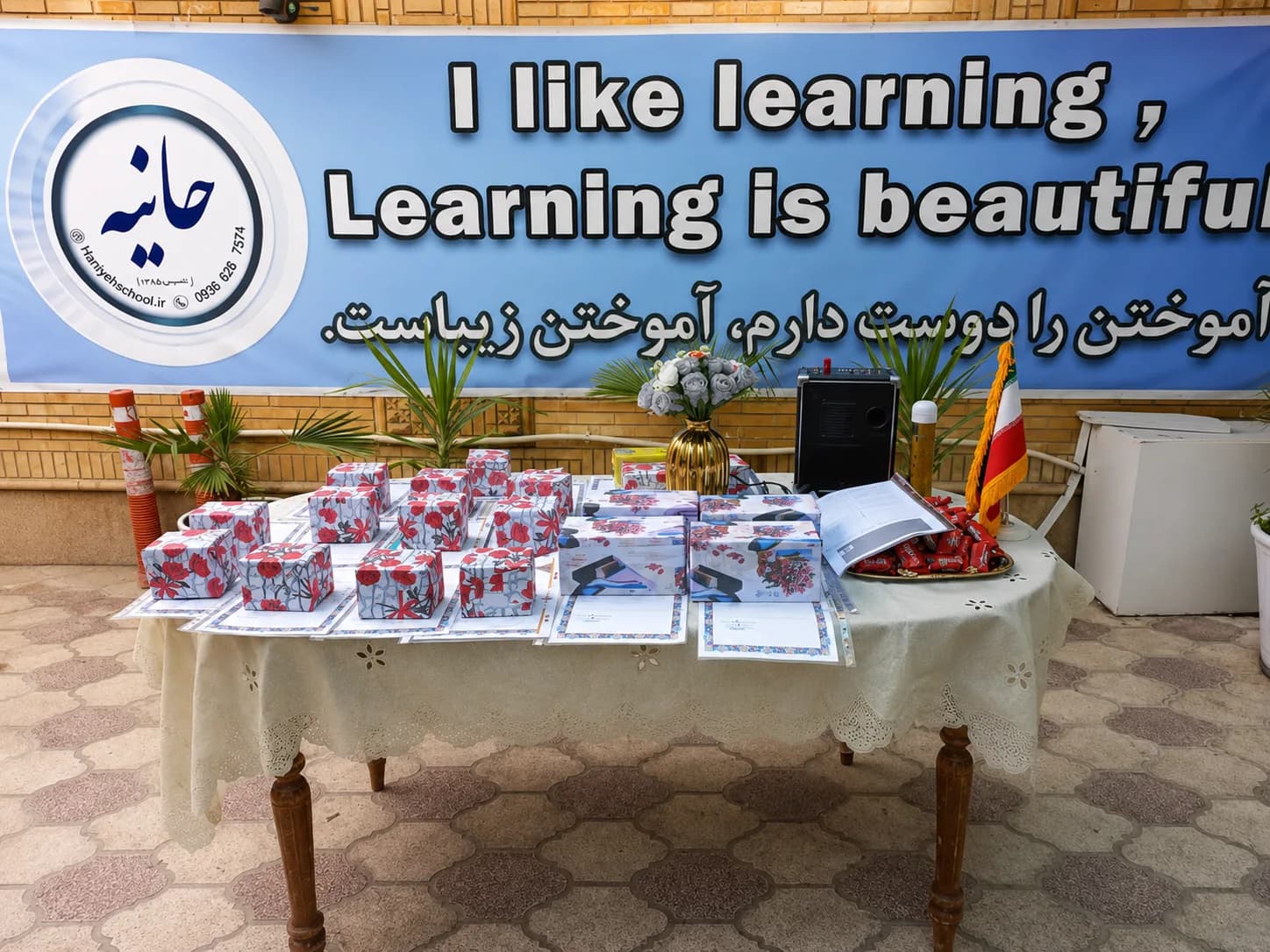 میز خوشآمدگویی با بنر «آموختن را دوست دارم» و نشان مجتمع آموزشی حانیه